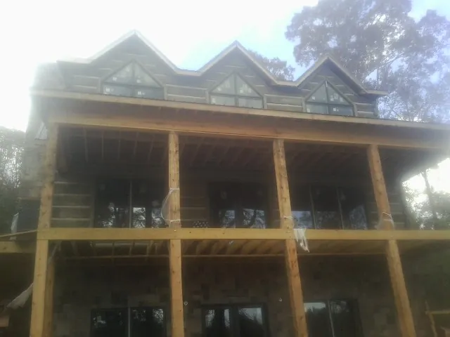 Dormers and porch framing on a large log home under construction — Roof Coating work by our crew in Pearl City