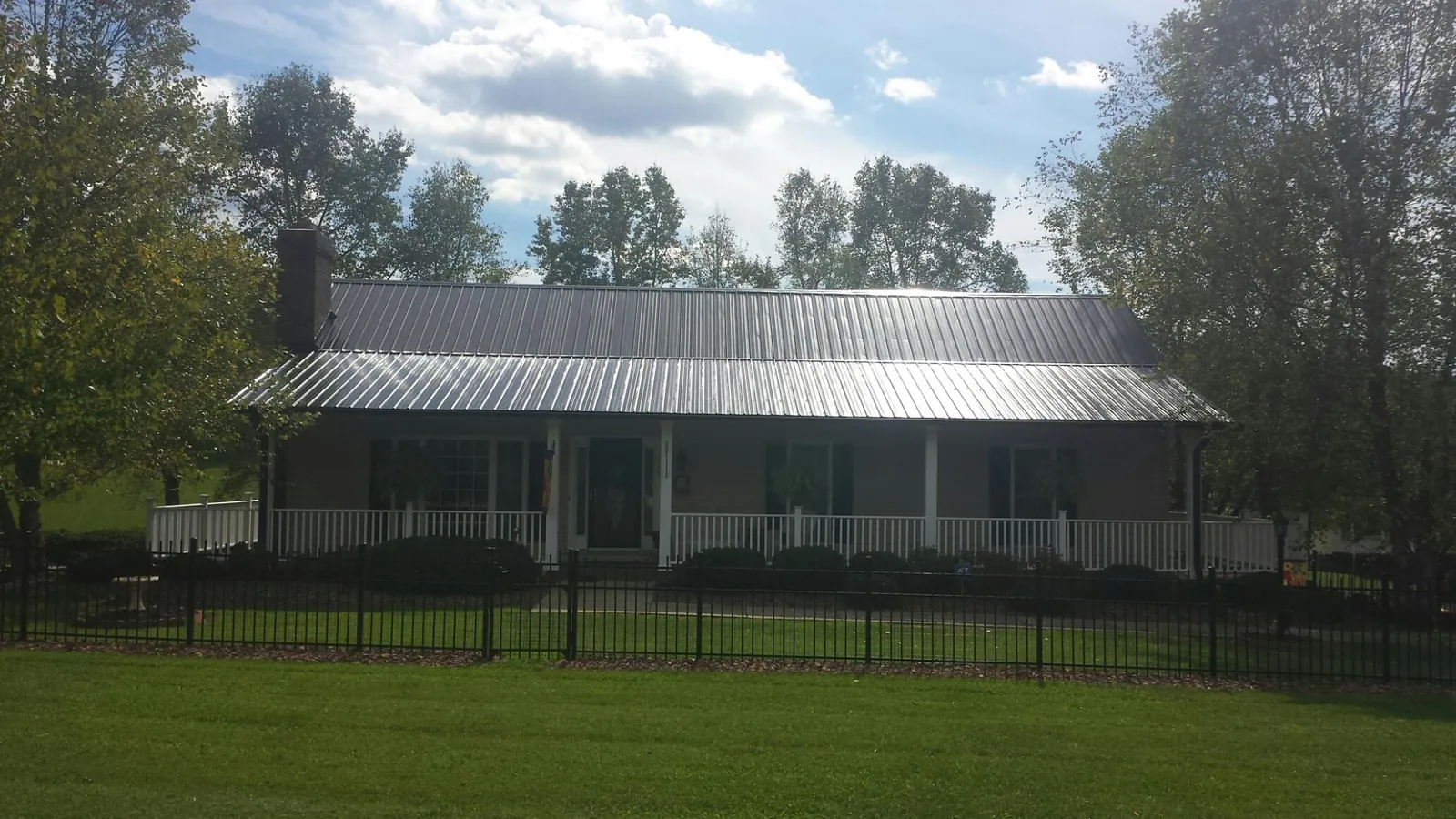 Gray metal roof on a brick ranch with a full width front porch — Gutter Guard Installation work by our crew in Pearl City