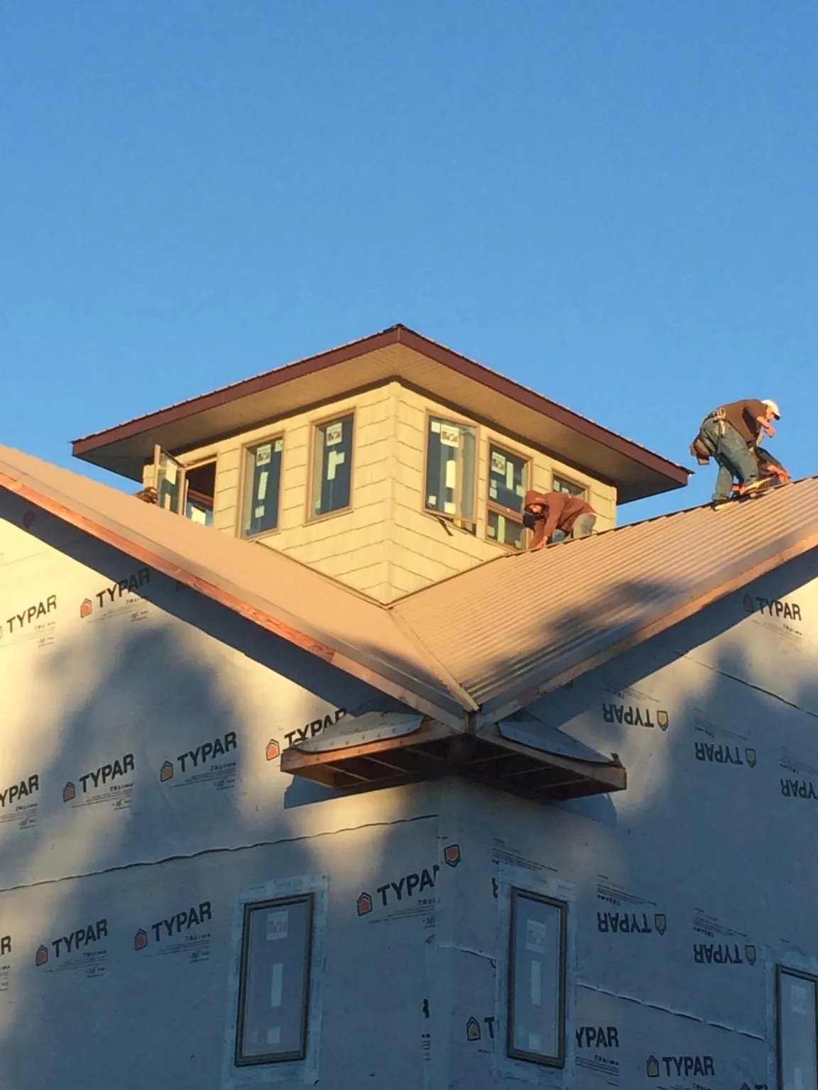 Roofers working around a rooftop cupola on a new metal roof at sunset — Roof Waterproofing in Pearl City by Roofing Brothers